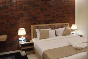 德拉敦Hotel Royal Palm Dehradun的一间卧室设有两张床和砖墙