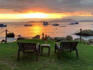 Praia do BananalFauna的两把椅子和一张桌子,享有水上日落美景