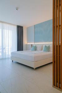 卡奥莱THE ONE CAORLE - Hotel & Apartments的卧室配有带蓝色枕头的大型白色床