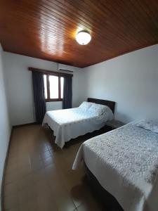 恩卡纳西翁AparWil的一间卧室设有两张床和木制天花板
