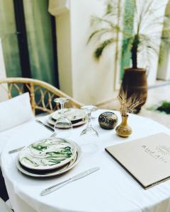 马拉喀什Riad Alia的一张带盘子和酒杯的白色桌子