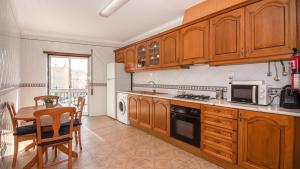 阿尔图拉Altura Vacations T2, Algarve的厨房配有木制橱柜、桌子和微波炉