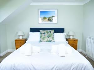 圣彼得港Ellingham Self-Catering Cottages的一间卧室配有白色床和2个床头柜