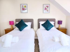 圣彼得港Ellingham Self-Catering Cottages的配有白色床单和蓝色枕头的客房内的两张床