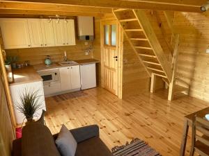 BodzentynDomek na Wsi的小木屋内的客厅设有厨房和楼梯