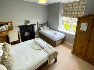 兰戈伦The Farm House的一间卧室设有两张床和一个壁炉。