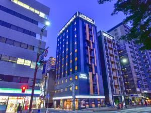 福冈HOTEL LiVEMAX Hakata Nakasu的夜幕降临的城市街道上一座高大的蓝色建筑