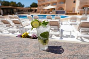 圣安东尼奥Rosamar Ibiza Hotel的在游泳池旁的桌子上喝一杯