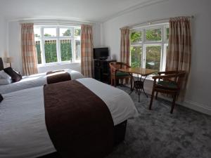 法尔茅斯The Grove Falmouth的酒店客房带两张床和一张桌子以及椅子。