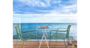 依拉佩特拉佩特拉马雷酒店的阳台上配有两把椅子和一张桌子,享有海景