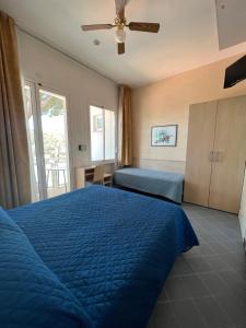 里米尼Hotel Villa dei Fiori - sul mare con piscina的一间卧室设有蓝色的床和窗户。