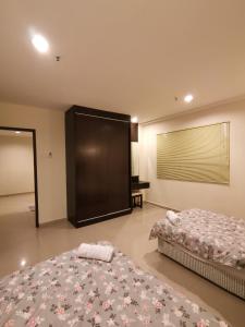 卢穆特Spacious & Homey Apartment at Marina Island by JoMy Homestay的一间卧室设有两张床和大屏幕