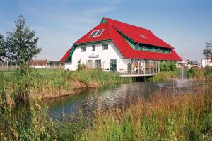 KreptitzFerienparadies Rugana D09的池塘顶部有红色屋顶的房子