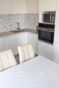 马马亚RoApart Mamaia- Sunset Dream的厨房配有两把白色椅子和微波炉