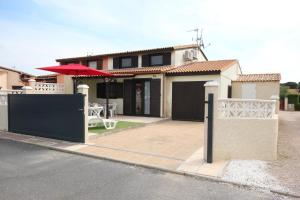 波尔蒂拉盖Belle villa de vacances climatisée, residence TAMARIS, wifi, 2 chambres 4 à 6 couchages, accès payant pour les piscines et animations , PORTIRAGNES PLAGE LRTAMA57的街上有带桌子和遮阳伞的房子