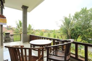 乌布Putra Bisma Guesthouse的阳台配有桌子和两把椅子