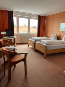 吕本山麓诺伊施塔特诺伊施塔特尔加尼霍夫酒店的酒店客房配有两张床、一把椅子和一张书桌