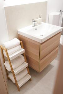上拉德戈纳Fado Apartments Gornja Radgona的浴室配有水槽、木制梳妆台和毛巾。