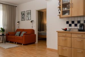 格拉茨Fresh Apartment with Terrace + Free Parking的一间带橙色沙发的客厅和一间厨房