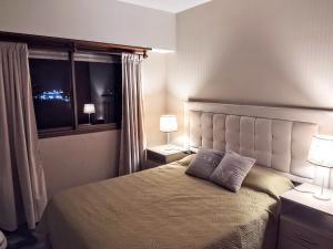 马德普拉塔VISTAS DEL GOLF的一间卧室配有一张带两盏灯的床和一扇窗户。