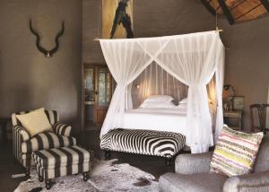提姆巴瓦提禁猎区Motswari Private Game Reserve by NEWMARK的一间卧室配有一张带天蓬的床和两把椅子