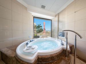 神户神户海港拉套房酒店的一个带大窗户的客房内的按摩浴缸