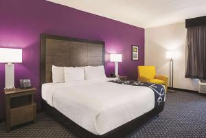 弗吉尼亚海滩弗吉尼亚海滩拉昆塔套房酒店的酒店客房设有一张大床和紫色的墙壁。