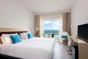 卡帕里卡海岸TRYP by Wyndham Lisboa Caparica Mar的酒店客房设有两张床、一张书桌和一个窗户。