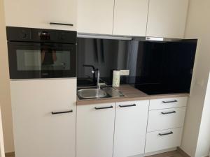 HerzeleQ Studio的厨房配有白色橱柜和黑微波炉