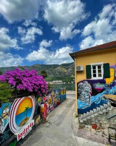 科托尔Montenegro Hostel 4U的紫色花朵旁边的墙上的壁画