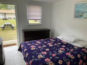 默特尔比奇Riviera Motor Lodge的一间卧室配有一张带花卉图案的毯子和窗户的床。