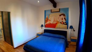 博洛尼亚La casa di Sacco - Appartamento Bologna Centro的卧室配有蓝色的床和墙上的绘画作品