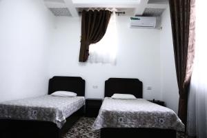 布哈拉Demir Hotel Bukhara的配有2张床的白色墙壁和窗帘