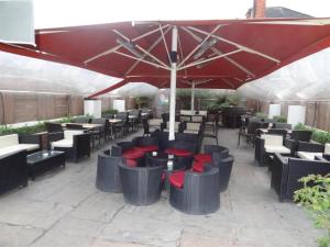 伦敦优尼科酒店的一个带桌椅的红色遮阳伞下庭院