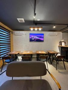 札幌Arura Sapporo的配有桌椅的教室和墙上的电视