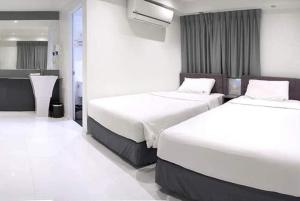 曼谷My Hotel Pratunam的配有白色墙壁的酒店客房内的两张床