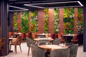 法马古斯塔Novel Centre Point Hotel的餐厅墙上挂有桌椅和植物