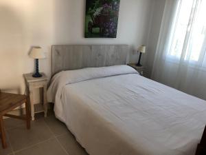 迈阿密普拉特亚Apartamentos Miradores的卧室配有一张白色床、两张桌子和两盏灯。