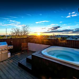雷克雅未克ICELAND SJF Villa, Hot tub & Outdoor Sauna Amazing Mountains and City View Over Reykjavík的甲板上的热水浴池,享有日落美景