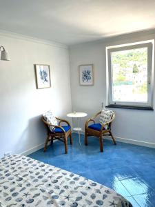 阿纳卡普里Attico Panoramico的一间卧室配有两把椅子、一张桌子和一个窗户。