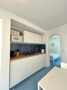 阿纳卡普里Attico Panoramico的厨房配有白色橱柜、微波炉和桌子