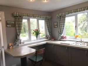 卡伦德Pinetree Cottage, dog friendly, Holiday let, Callander Invertrossachs的厨房配有桌子、两个窗户和一个水槽