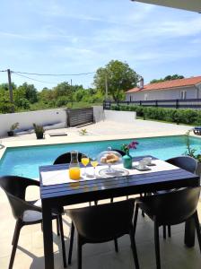 ManjadvorciVilla VINE - new luxury holiday house in a green oasis的一张桌子,在游泳池边用餐