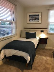 德文港Silwood Apartment fully self contained with Kitchen and Laundry的一间卧室配有一张带黑色毯子的床和两个窗户。
