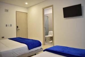 库库塔Hotel Blu Cúcuta的一间带两张床的卧室和一间带卫生间的浴室
