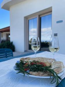 卡拉古诺内Hotel Pranos Turismo Rurale Cala Gonone的桌上放着一盘食物和两杯酒杯