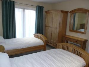 彭里斯Cherry Lodge的一间卧室配有两张床、一个梳妆台和镜子