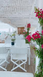 利迈纳里亚Hotel Samaras Beach的一间设有白色桌子和白色椅子及鲜花的房间