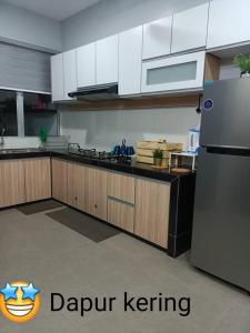 Kampong Sungai Che LiasSalju Mewah Homestay的厨房配有白色橱柜和不锈钢冰箱