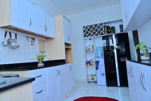 KiraCheerful 3-Bedroom Home in a Family Setting的厨房配有白色橱柜和黑色冰箱。